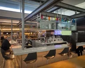 A modern, well-stocked airport bar with a few patrons.