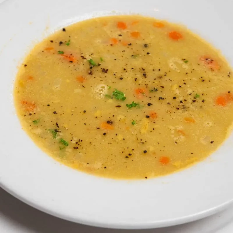 Close-up of a bowl of split pea soup with carrots and parsley.