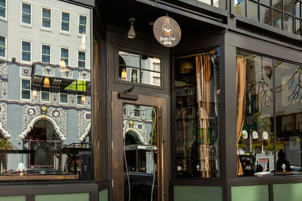 Reflections of ornate gray building and street visible on pub windows.