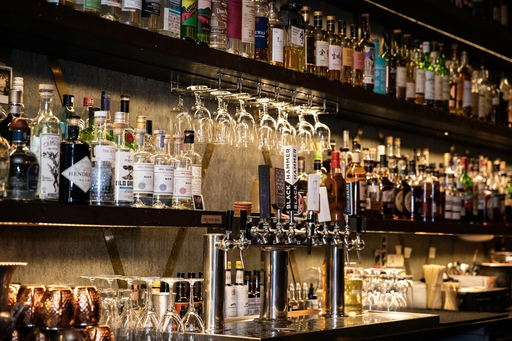 A well-stocked bar with bottles, glasses, and beer taps.