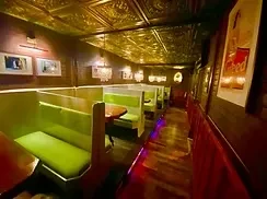 Narrow restaurant with green booths, dark walls, and golden ceiling.
