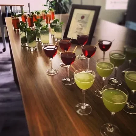 A wooden bar with multiple rows of various colorful cocktails.