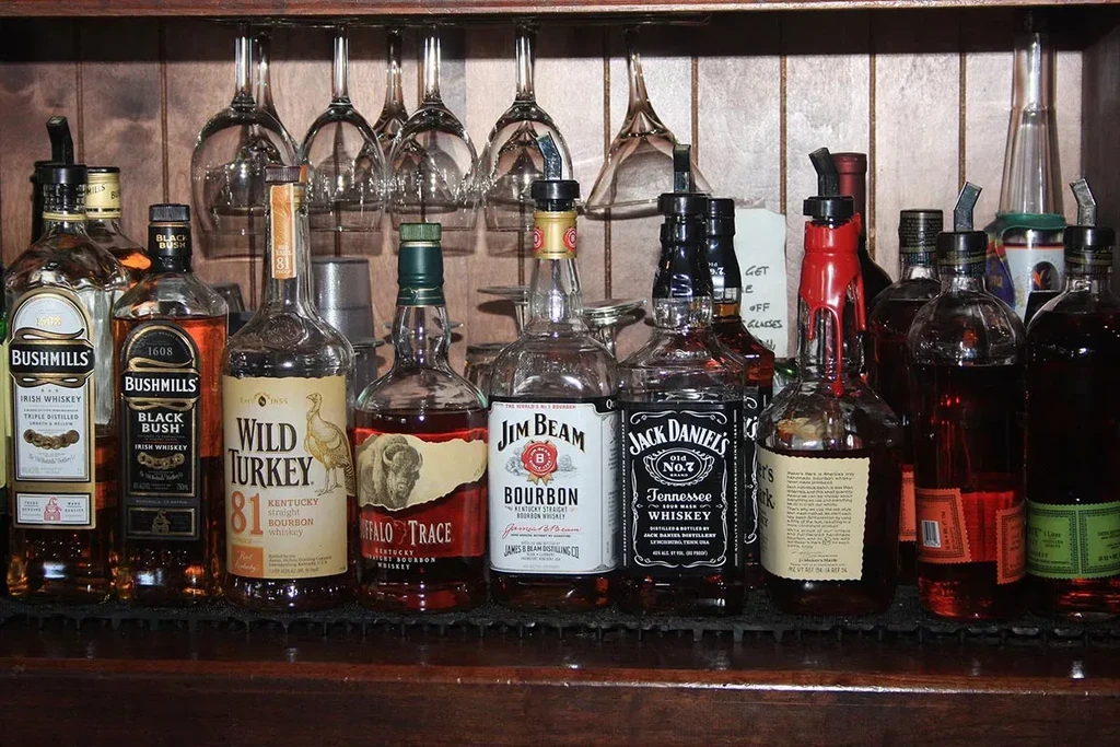 Assortment of liquor bottles including Bushmills, Wild Turkey, Jim Beam, and Jack Daniel's.