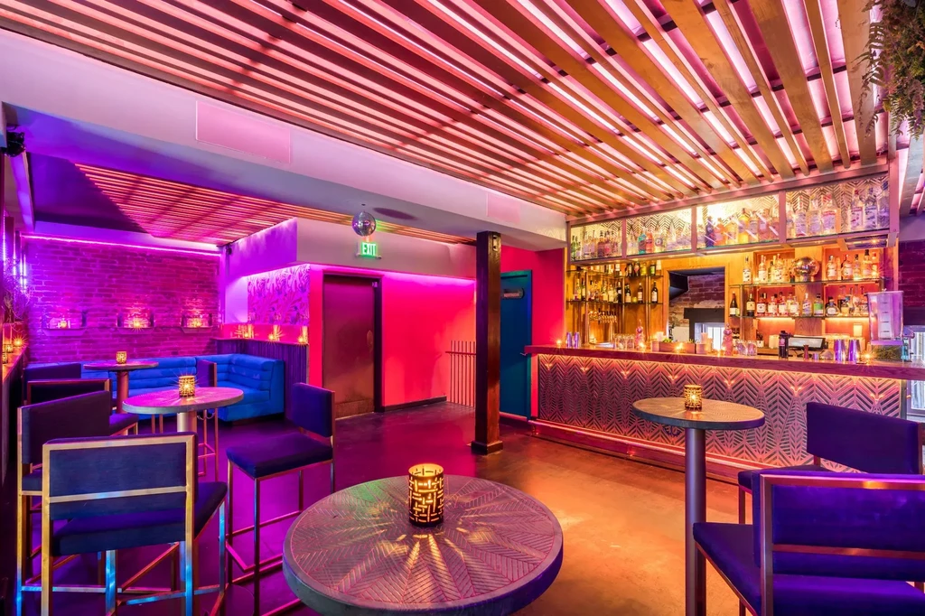 A vibrant bar with purple, pink, and orange neon lighting.