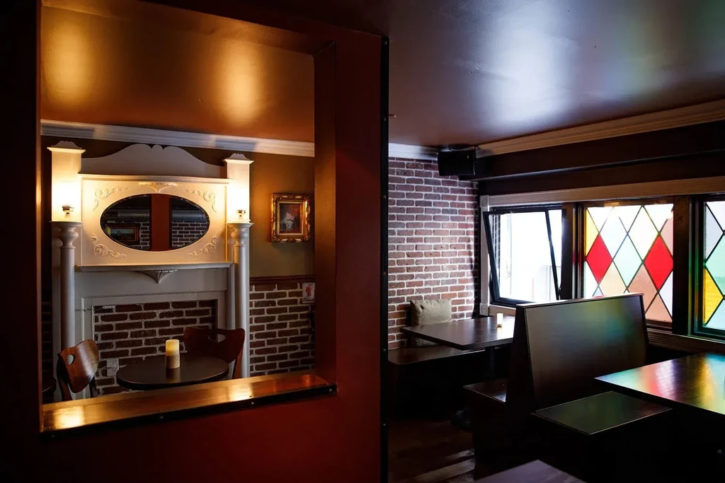 An interior of a restaurant showing two rooms with brick walls.