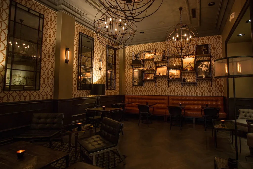 A dimly lit room with vintage decor, orange wallpaper, and various seating.