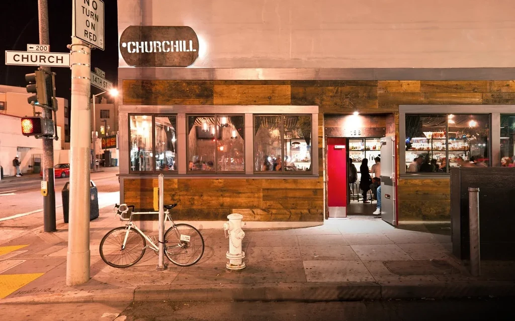 A bar at night with a red door and a bike parked outside.