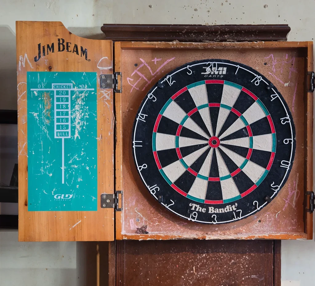 An old, open wooden dartboard cabinet with a "Jim Beam" logo.