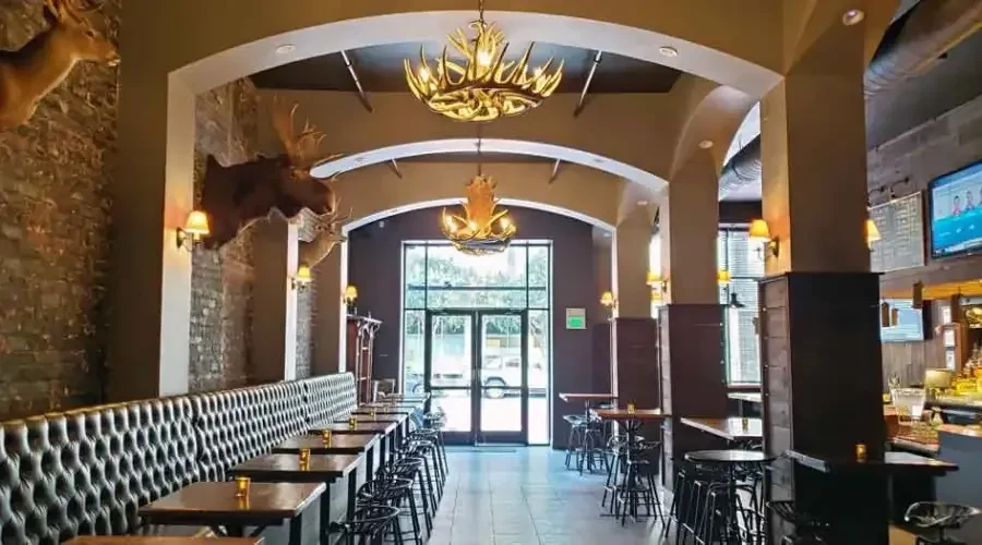 A dim bar or restaurant with antler chandeliers and animal mounts.