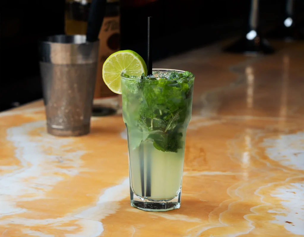 A mojito with lime and mint on a bar.