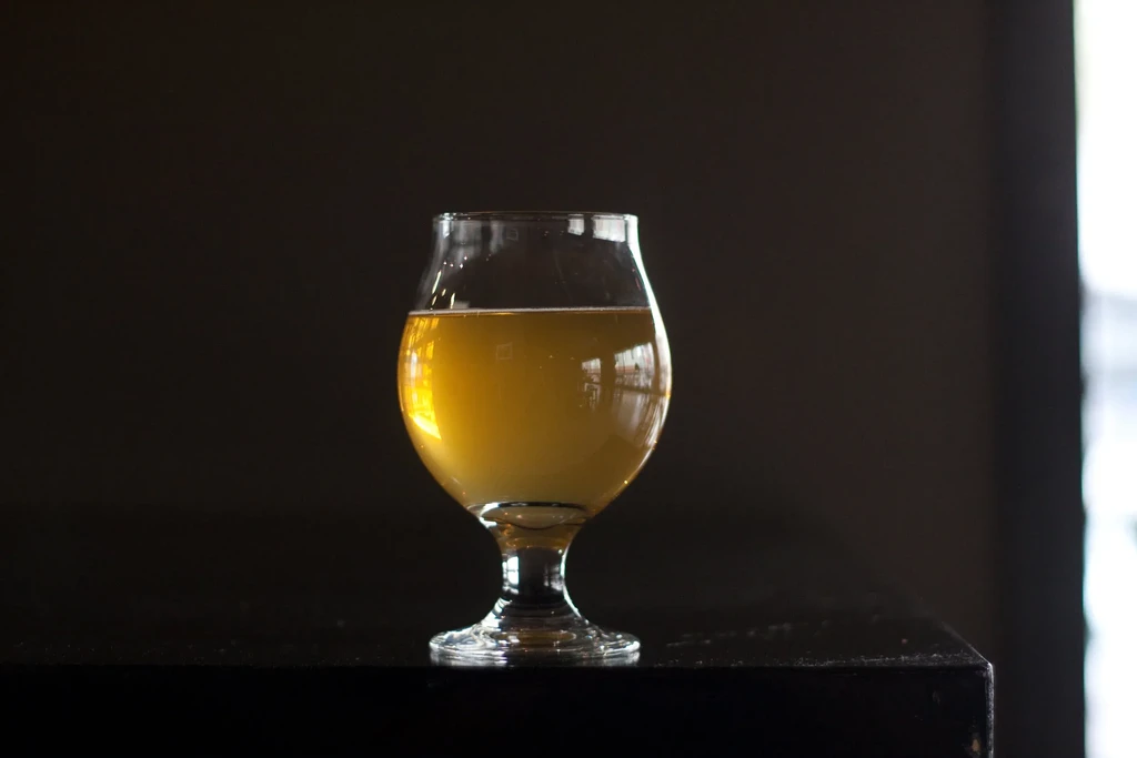 A snifter glass filled with golden liquid on a dark surface.