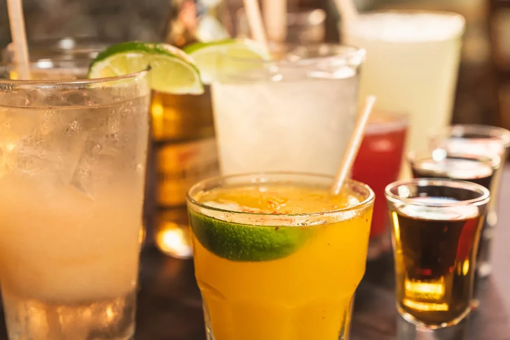 Various drinks and shot glasses on a blurred background.