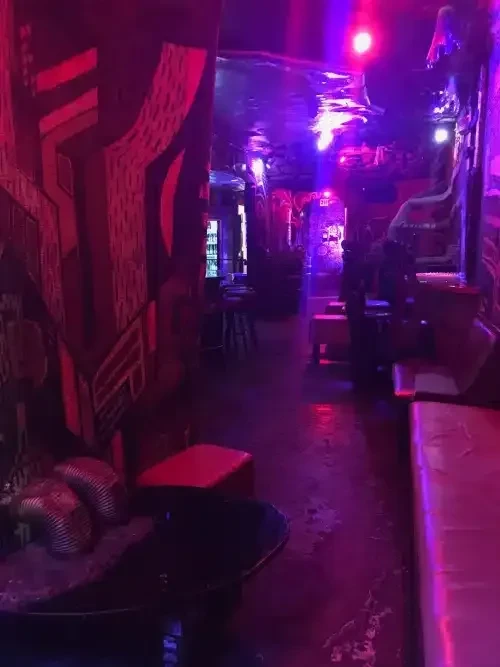 A dark, long room bathed in red and purple neon light.