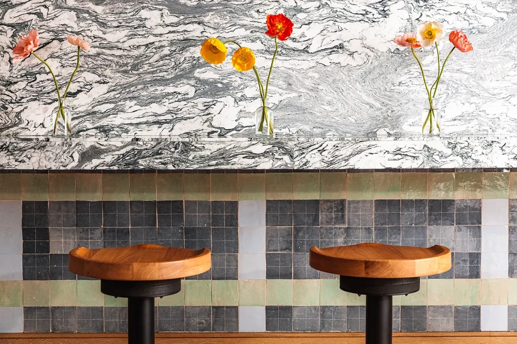 Bar with three vases of poppies, marbled wall, and tile backsplash.