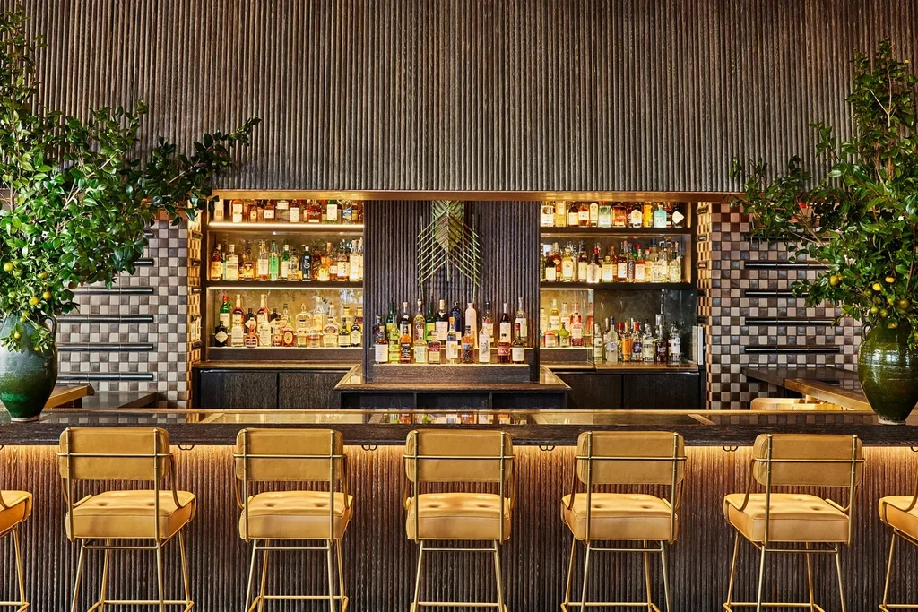 A luxurious bar with shelves of liquor bottles and leather bar stools.