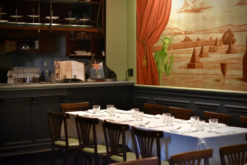 Restaurant dining room with bar counter and wall mural of green figure.