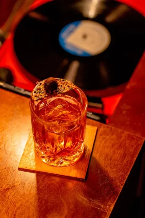 An amber drink in a glass with a record player in the background.