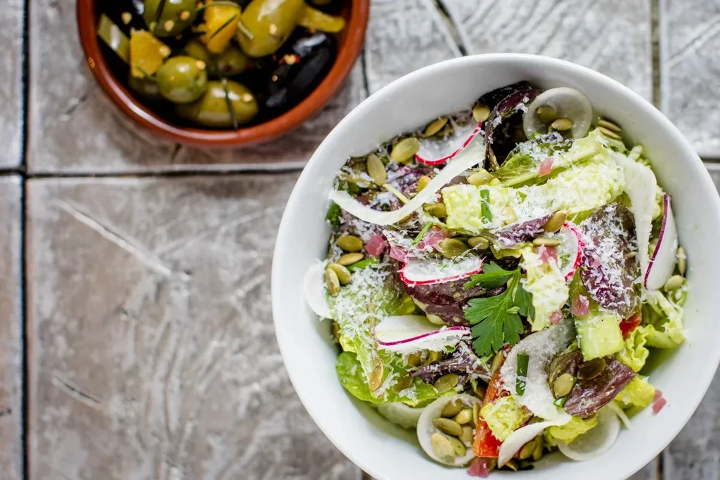 Overhead view of a salad bowl and a small bowl of olives.
