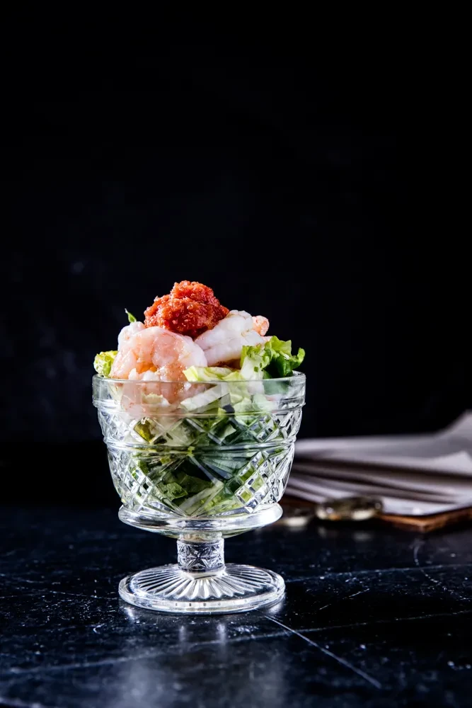 Prawn cocktail with lettuce and sauce in a cut glass dish.