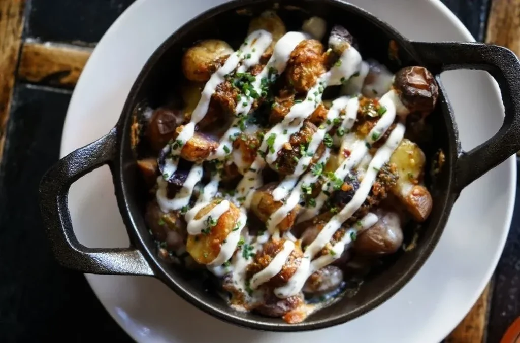 Roasted potatoes with sauce and chives in a cast-iron skillet.