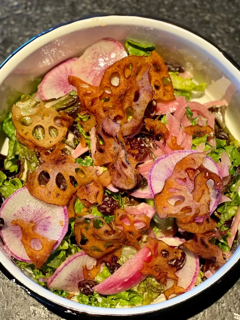 Close-up of a salad with lotus root chips, radishes, and lettuce.