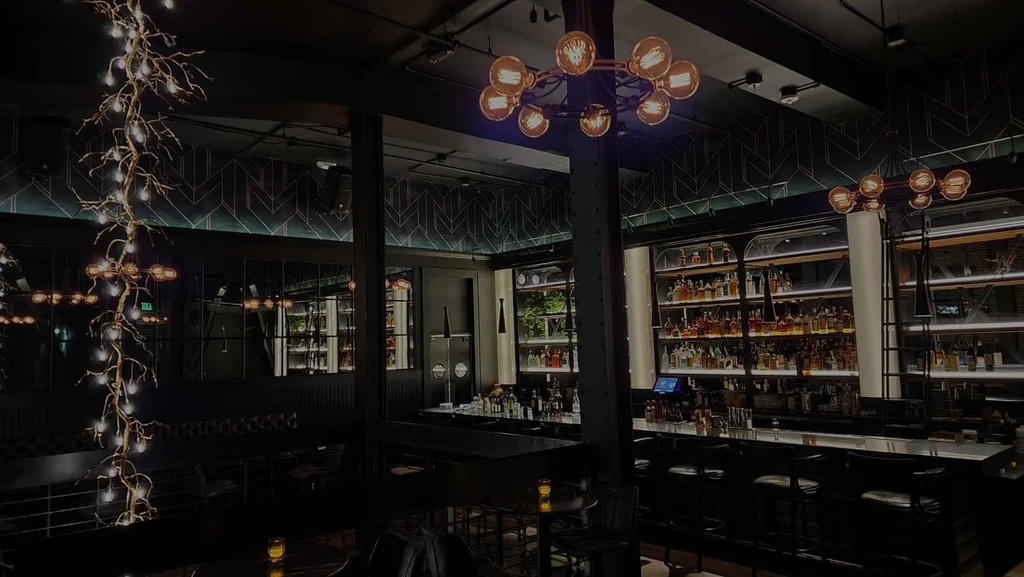 A dark bar with illuminated alcohol bottles and unique light fixtures.