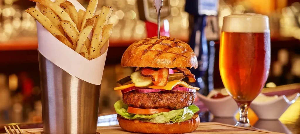 Hamburger with bacon, cheese, fries, and a beer.