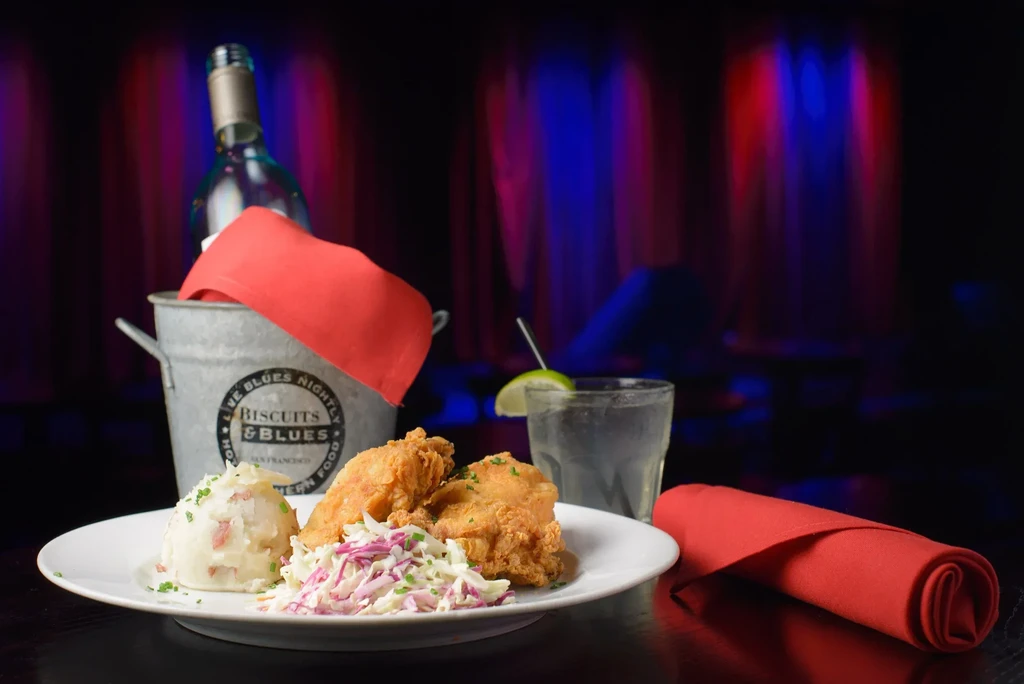 Fried chicken, mashed potatoes, coleslaw, and drinks at a restaurant.