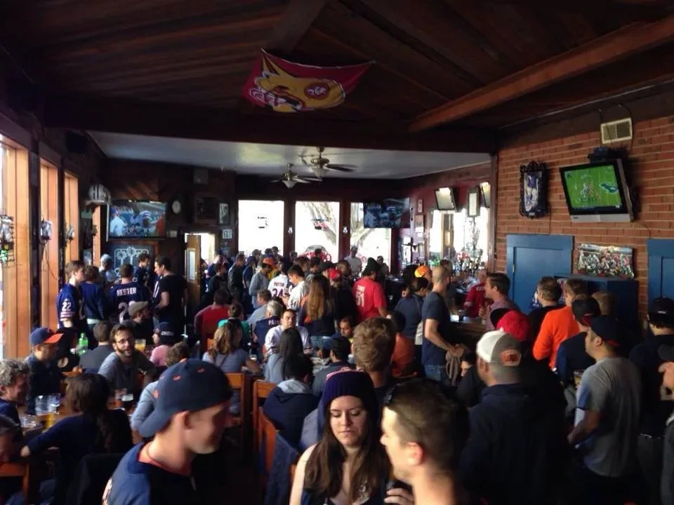 A crowded sports bar with people watching different games on multiple televisions.