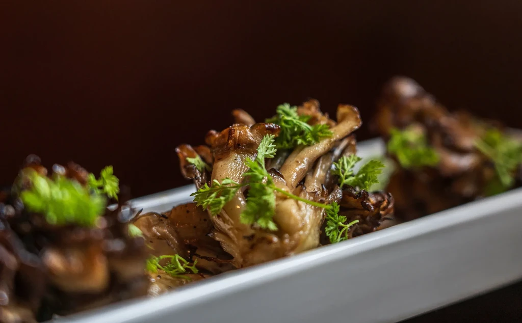 Sauteed mushrooms with fresh herbs served on a white rectangular plate.