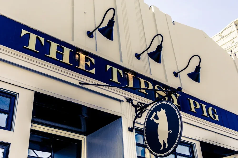 The Tipsy Pig pub sign with a pig holding a beer.