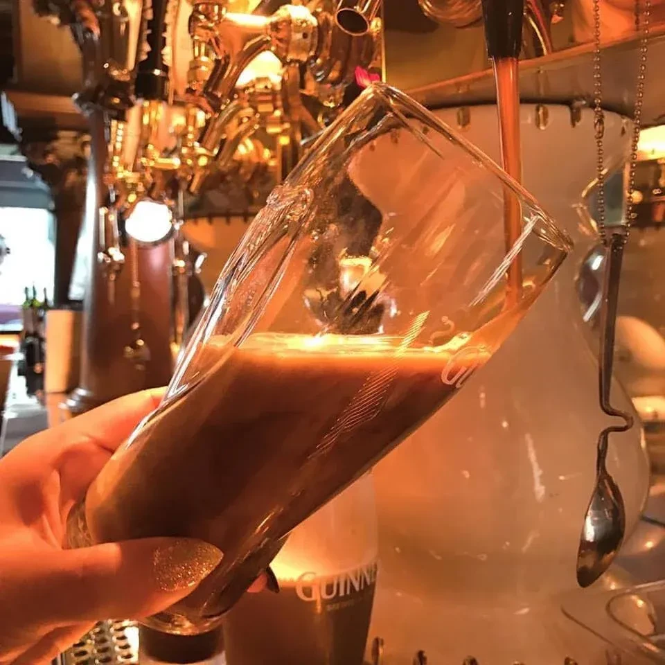 A Guinness beer being poured from a tap into a glass.