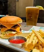 A double cheeseburger, fries, ketchup, and a beer with lime on a tray.