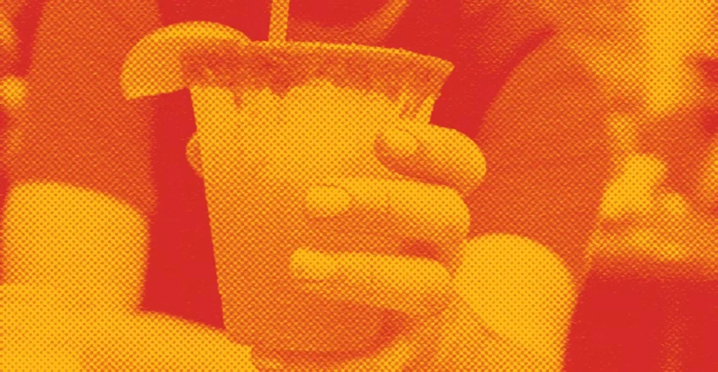 Halftone image of a hand holding a drink with a lime wedge.