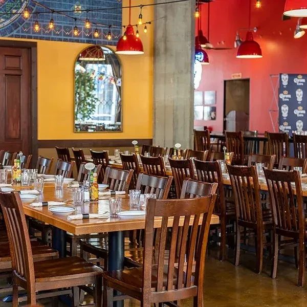 Empty dining room with wooden tables, chairs, and colorful walls.