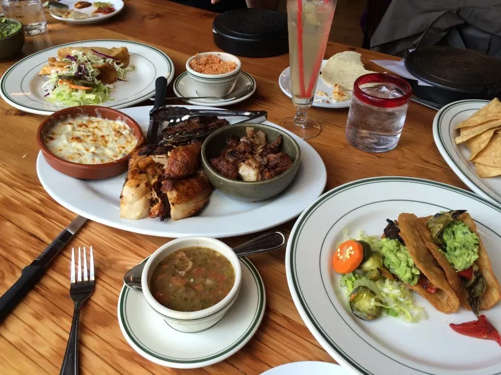 A table set with multiple plates of Mexican food and beverages.