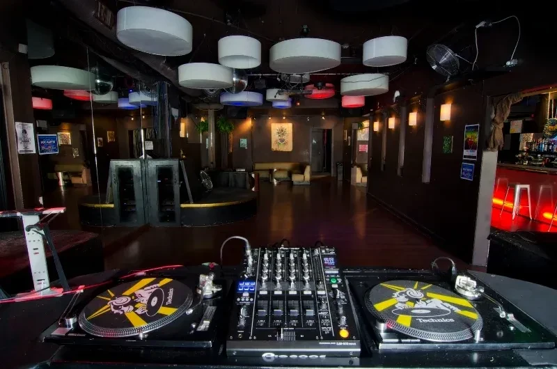 A DJ's turntables and mixer are in an empty nightclub.