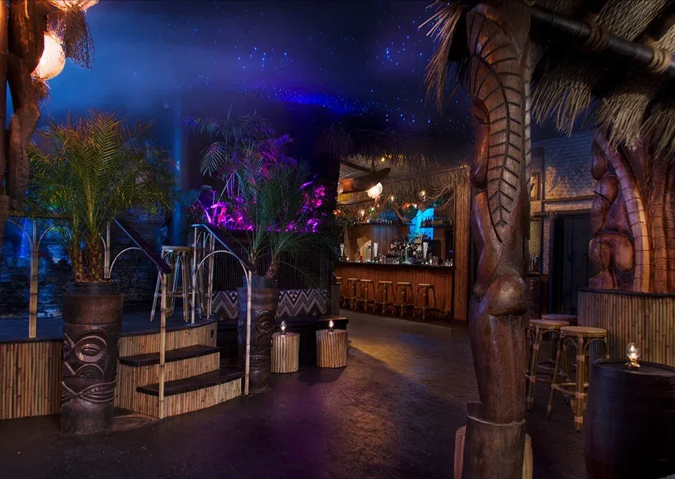 A vibrant tiki bar with glowing purple and blue lighting.