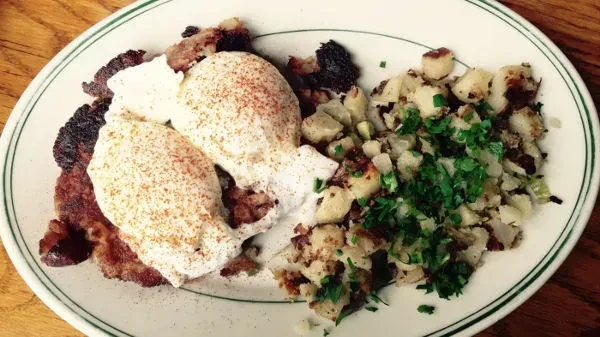 Two poached eggs over bacon and hash browns with parsley.
