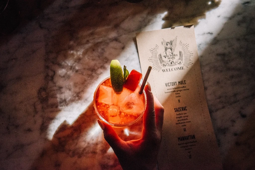 Hand holding a garnished cocktail next to a menu.