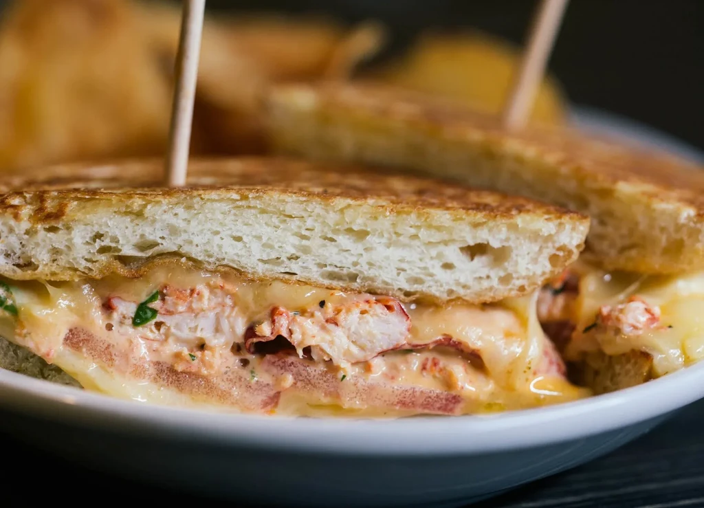 Close-up of a lobster grilled cheese sandwich with gooey melted cheese.