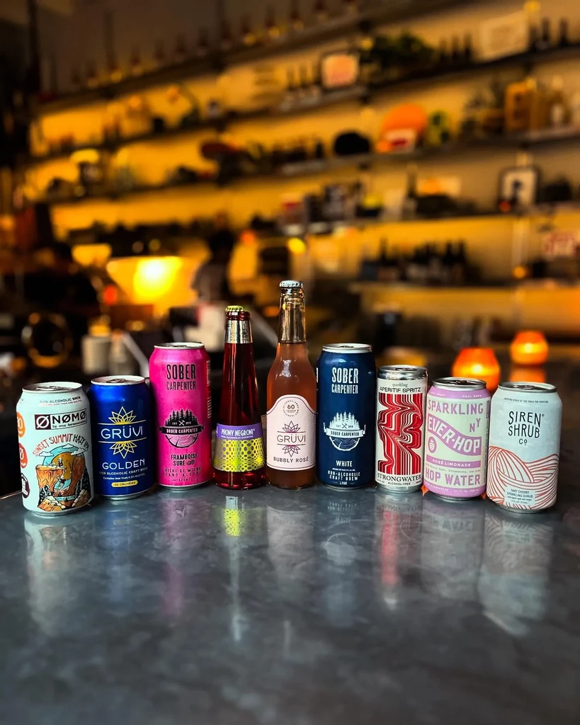 Nine non-alcoholic beverages are lined up on a reflective bar counter.