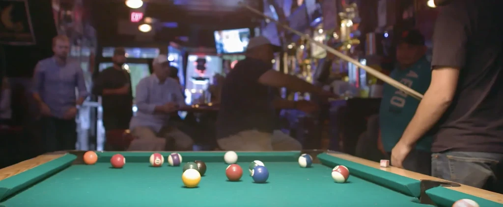 Several men playing pool in a dimly lit bar.