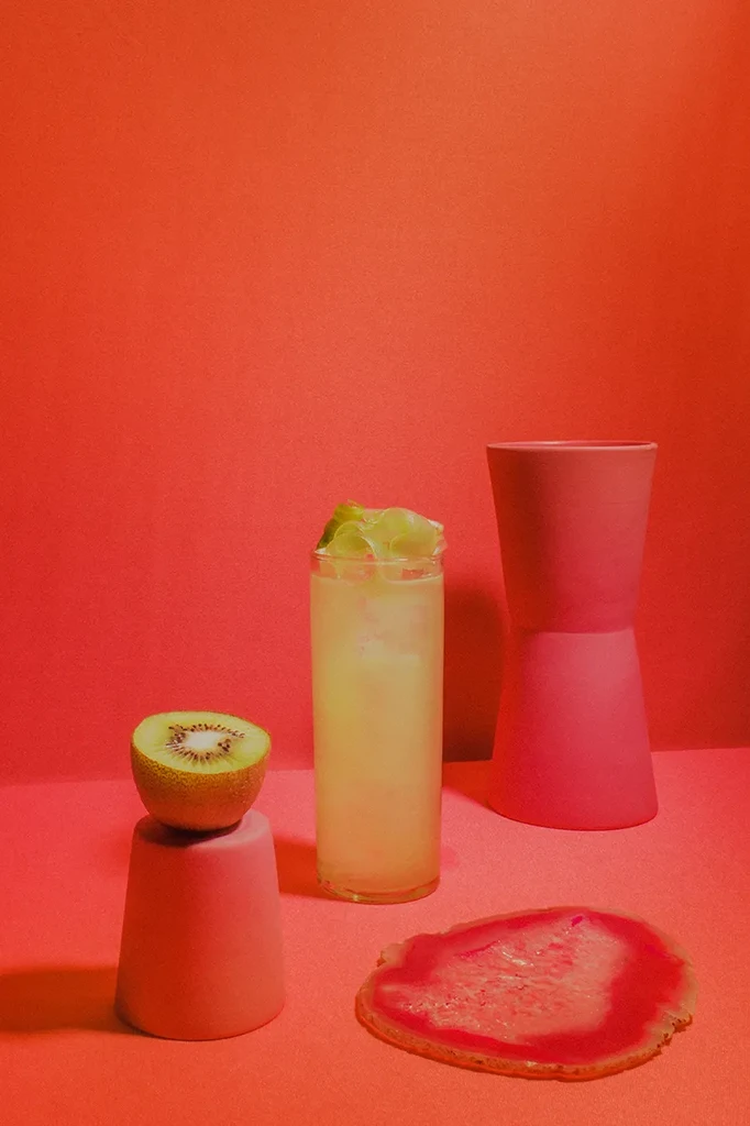 A drink, kiwi, and decor objects in a red-orange setting.