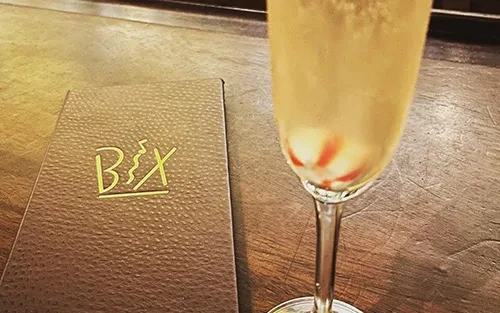 A menu with a BXY logo next to a champagne flute with candy.