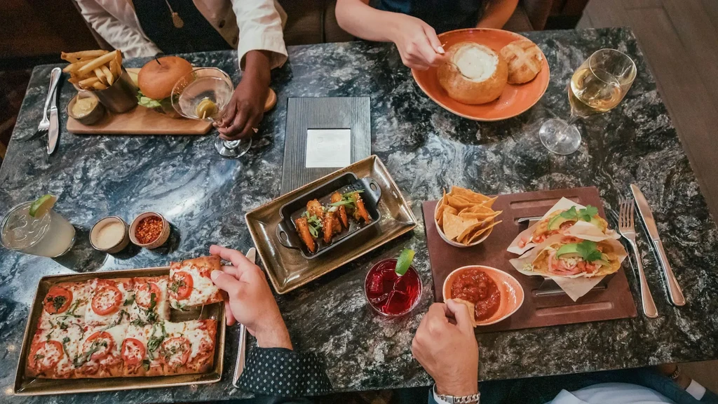 Overhead view of people enjoying a variety of restaurant dishes.