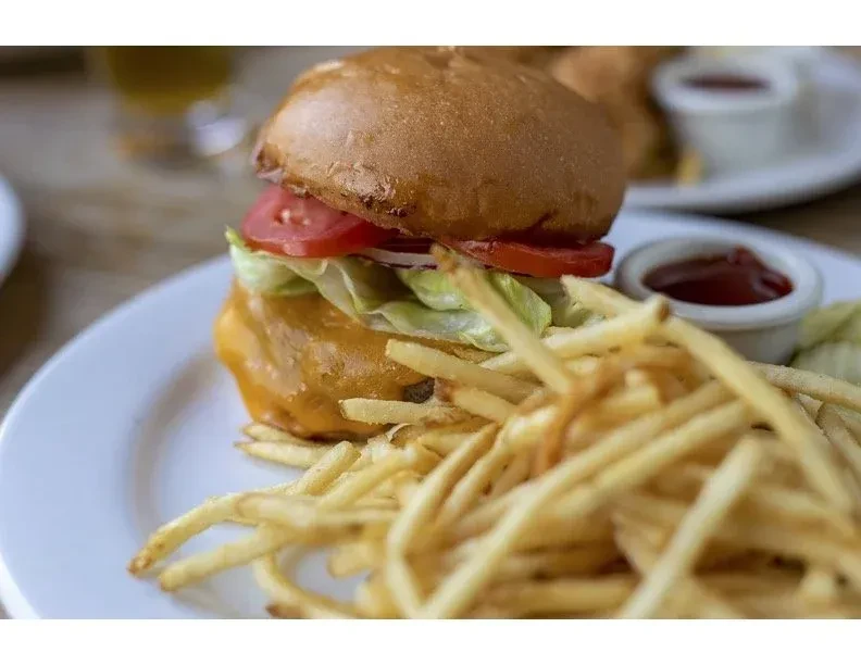 A cheeseburger with lettuce, tomato, and a side of french fries.
