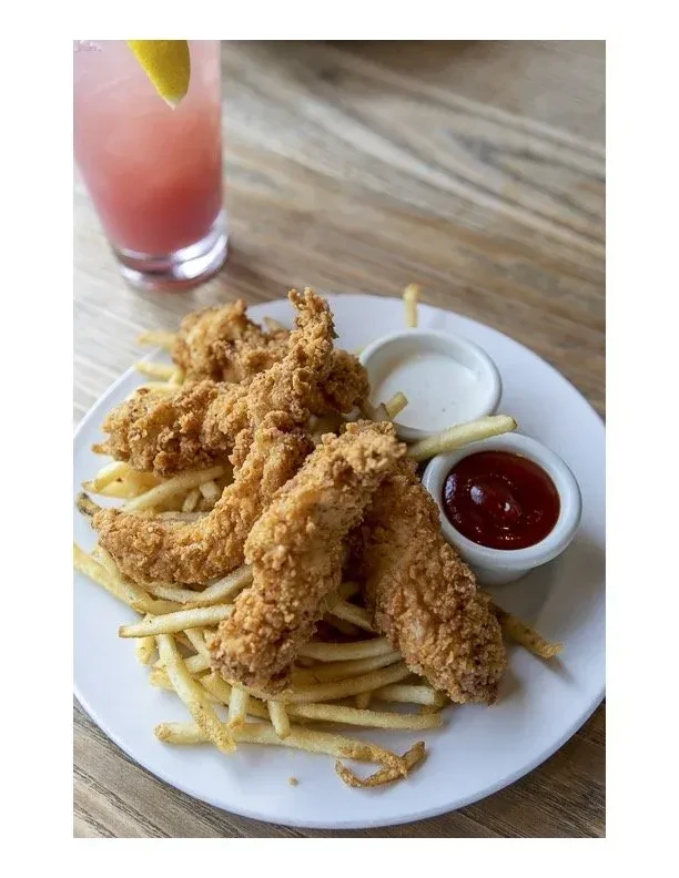 A plate of fried chicken tenders, french fries, ketchup, and a drink.