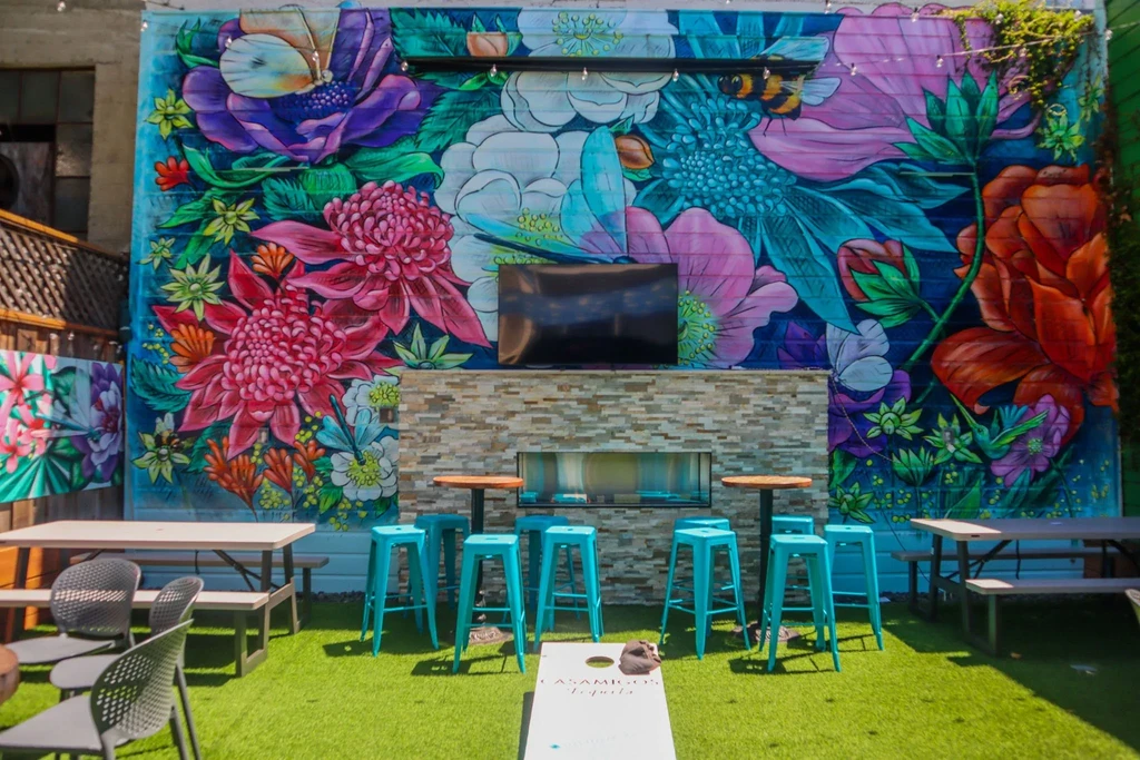 An outdoor patio with a colorful mural and fireplace.