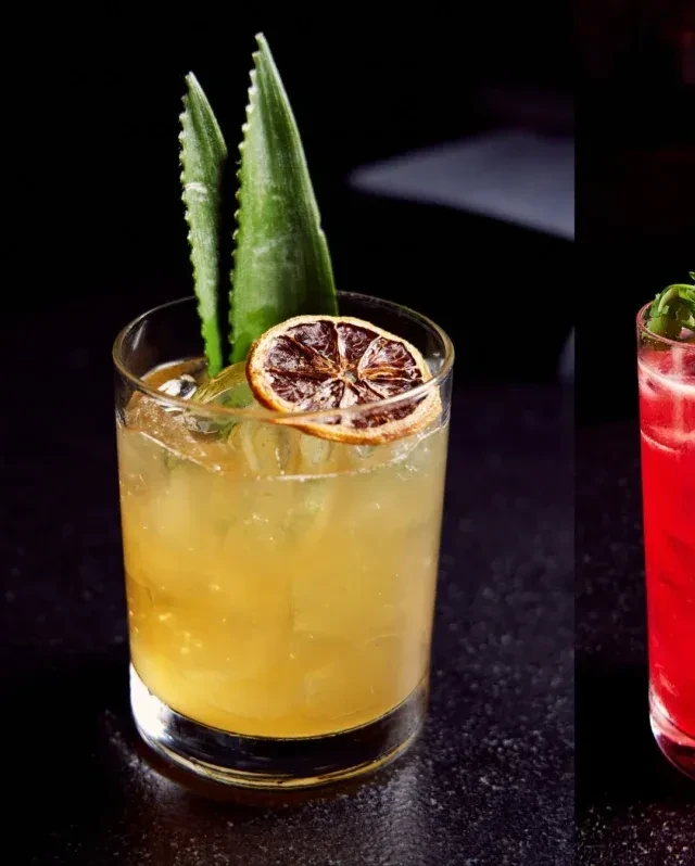 Two cocktails on a dark surface, one yellow, one red.